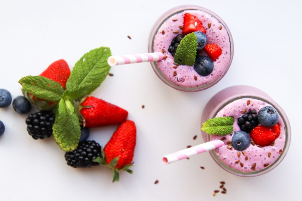 A bowl of blueberry smoothie with strawberry and blueberry on the table