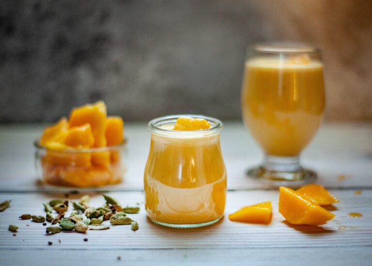 A glass of mango smoothie on top of a table