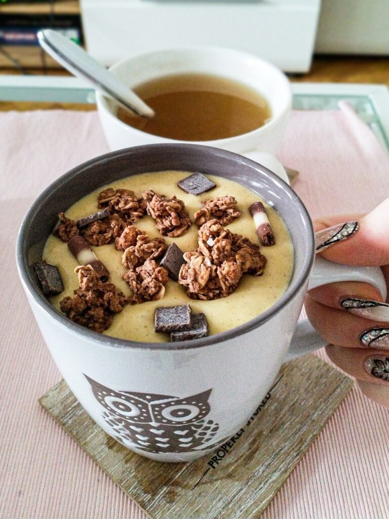 Chocolate protein smoothie in a decorative mug topped with some chocolates