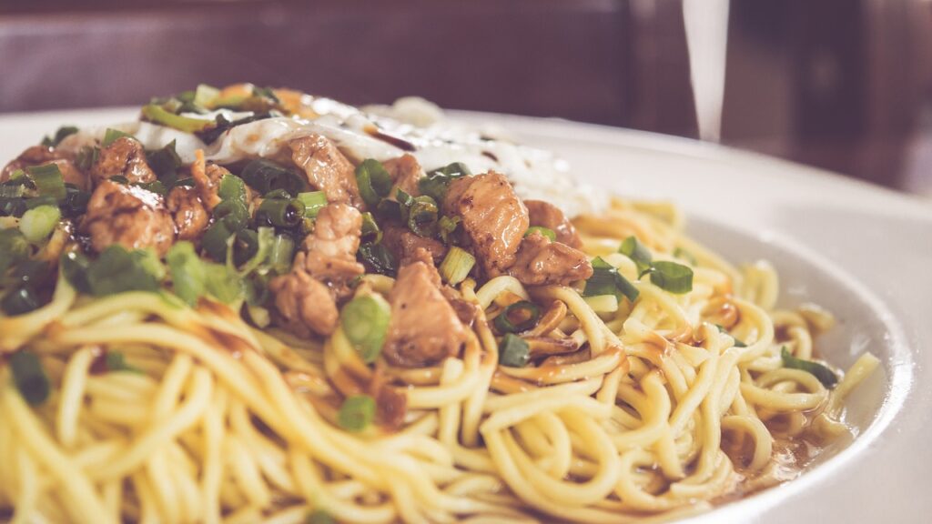 chicken with noodles placed on a white plate