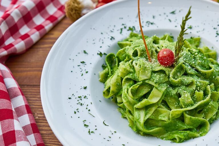 Green Pasta in a white plate placed on a table