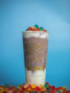 Glass of mocha drink with colorful jellies against blue background