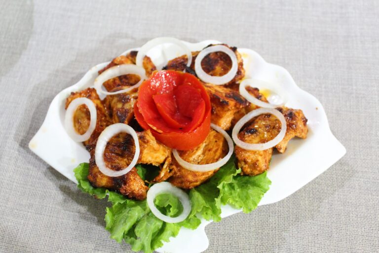 Tuscan chicken placed on white plate with onion garnishing on top